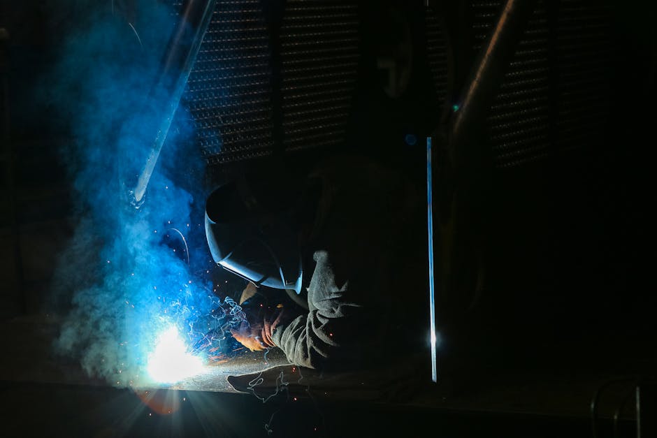A skilled welder wearing protective gear works on metal, emitting bright sparks and smoke.