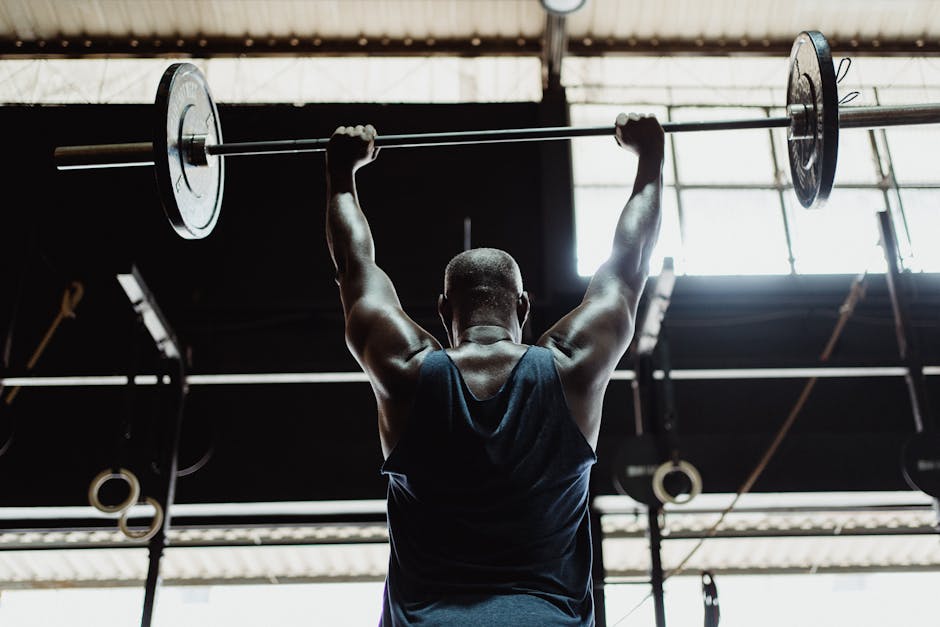 Man lifting barbell in gym from back view highlighting strength and fitness.