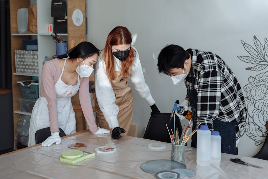 Three adults crafting with resin wearing masks and gloves in a studio.
